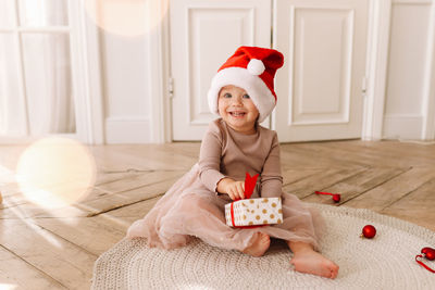 A cheerful emotional little child girl in red santa claus hats is having fun on christmas holiday