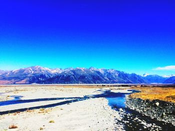 Scenic view of mountains against blue sky during winter