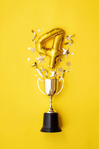 Directly above shot of trophy against yellow background