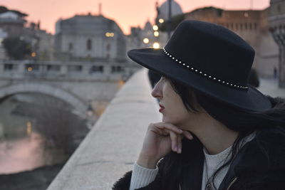 Thoughtful woman wearing hat looking away at bridge