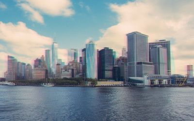 Modern buildings by river against sky in city