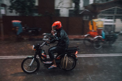 Man riding bicycle on road in rain