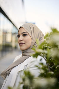 Portrait of smiling young woman standing against sky
