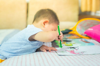 Boy drawing on book at bed