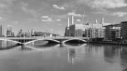 Bridge over river by buildings against sky