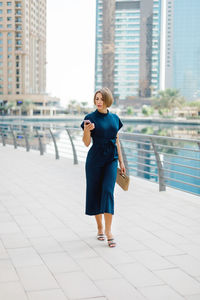 An attractive young woman using a smartphone while walking along the embankment