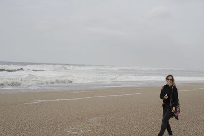 Woman walking at beach against sky