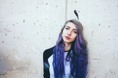 Portrait of a beautiful young woman standing against wall