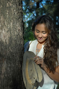 Young woman smiling with tree trunk