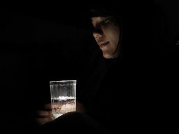 Midsection of man holding drink against black background