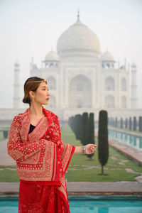 Young woman standing against historic building in india