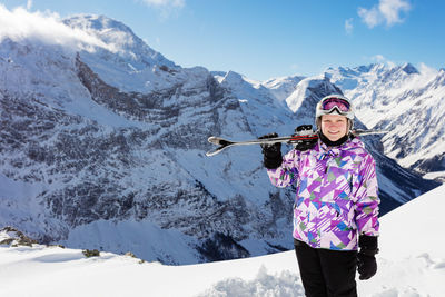 Portrait of woman standing on snowcapped mountains against sky