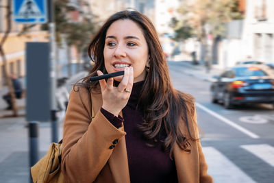 Portrait of smiling young woman holding street in city