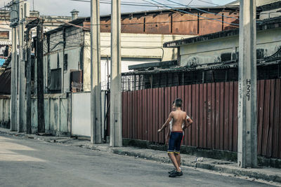 Rear view of man walking on street against buildings in city
