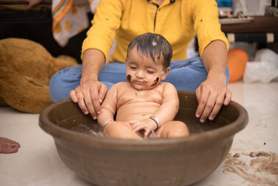 Midsection of man by girl in baby bathtub on floor