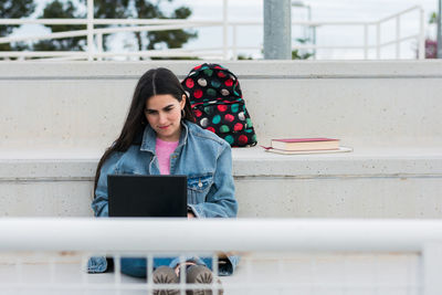 Young university student writes notes in her laptop on campus