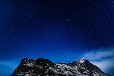 Low angle view of mountains against star field at night