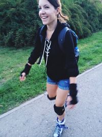 Full length of smiling young woman on road