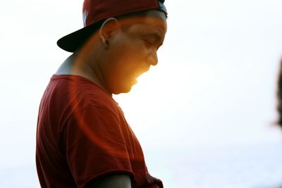 Portrait of young man looking away against sky