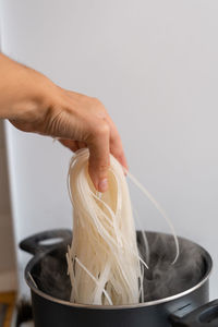 Cropped hand of person preparing food in bowl against white background