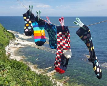 Clothes hanging by sea against sky