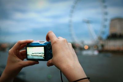 Cropped image of hands photographing millennium wheel