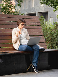 Freelance business woman sits in park with laptop. urban lifestyle of millennials. working remotely.