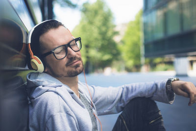 Man listening music while sitting on footpath