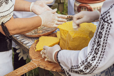 Woman's hands cut polenta on the table with romanian ornaments