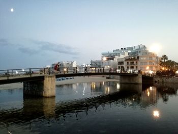 Buildings by river against sky in city