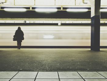 Rear view of woman standing at railroad station