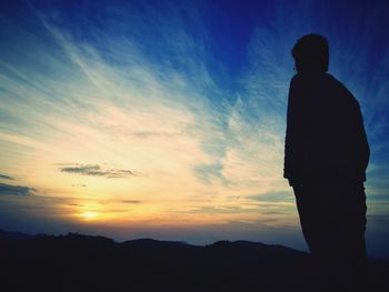 Rear view of silhouette man standing against sky during sunset