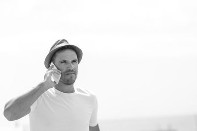 Man using mobile phone while standing against clear sky at beach