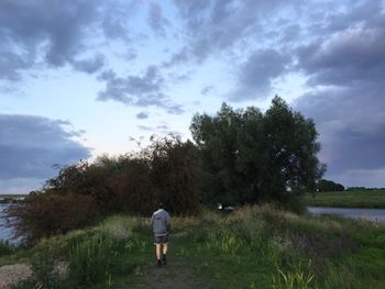 Rear view of man standing on landscape against sky