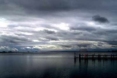 Pier on sea against cloudy sky