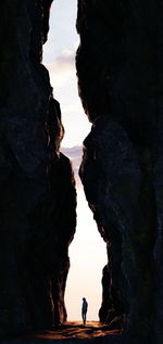 Silhouette people on rock formation against sky during sunset
