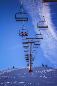 Low angle view of ski lift against sky during winter