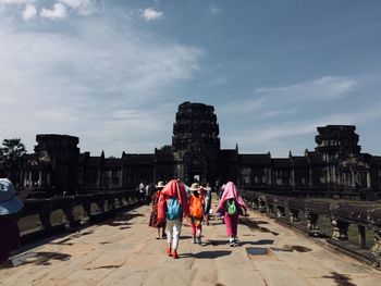 Rear view of people on historical building against sky