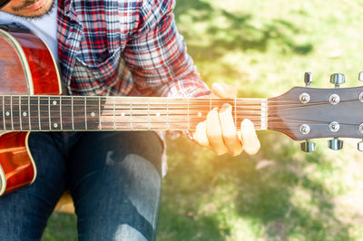 Midsection of man playing guitar