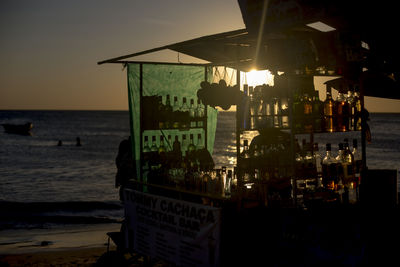 Built structure on beach against sky at sunset