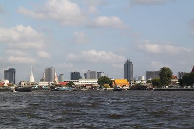 Sea by buildings against sky in city