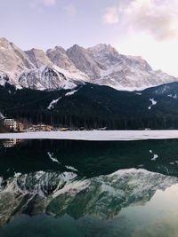 Scenic view of lake by snowcapped mountains against sky