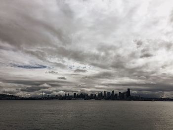 City at waterfront against cloudy sky