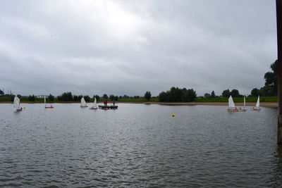 People sailing in river against sky