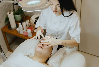 A girl cosmetologist makes a relaxing massage of a woman face.
