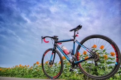 Low angle view of bicycle parked on field against sky