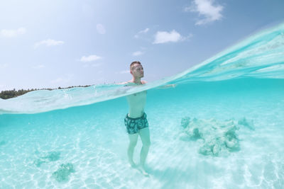 Man walking on sand seabed of beautiful turquoise sea. tourist enjoying beach holiday.