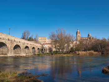 Bridge over river against clear blue sky