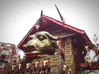 Low angle view of statue against temple against clear sky