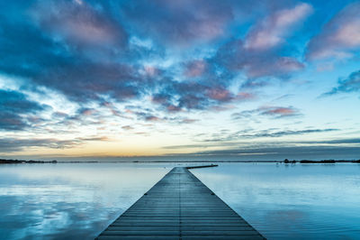 Pier over sea against sky during sunset